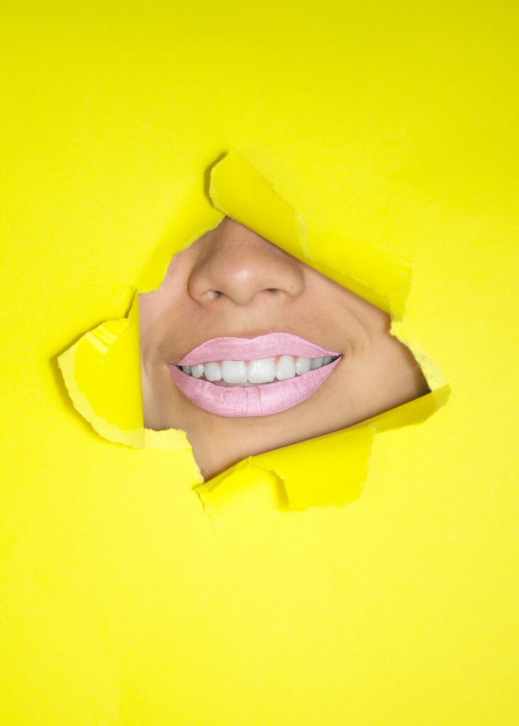 ripped yellow paper showing woman's nose and lips